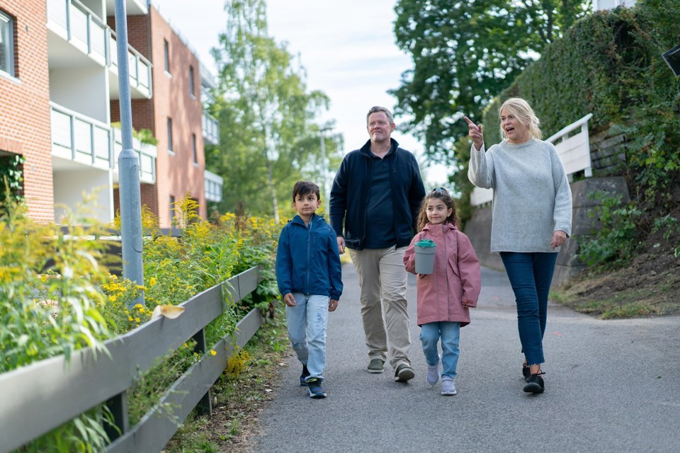 To voksne og to barn går i et nabolag. Et av barna holder en bøsse i hånda.