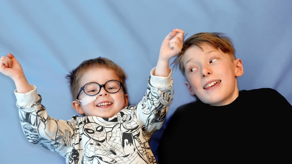 To unge gutter ligger ved siden av hverandre, en med briller og nesesonde.